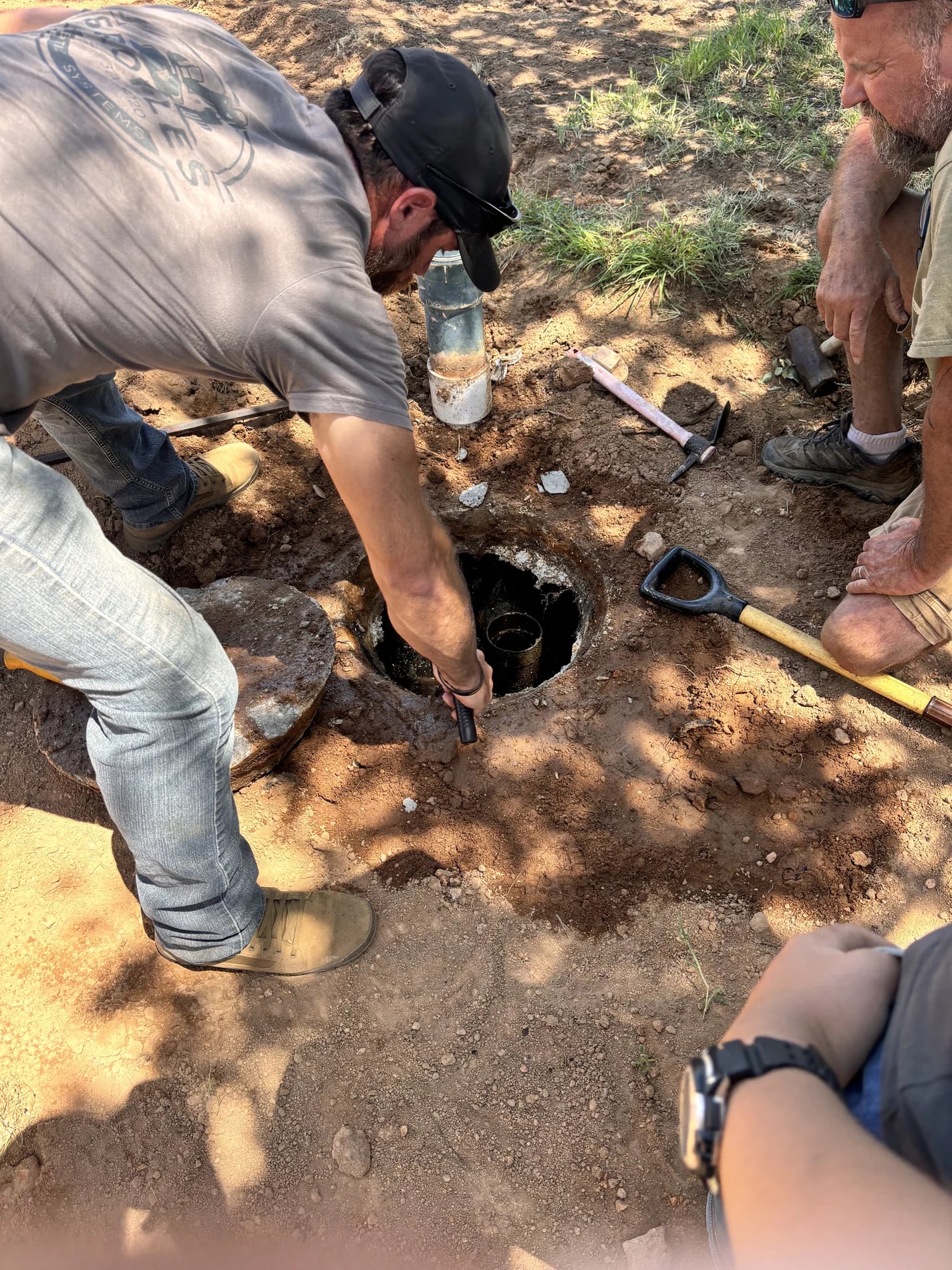 People working around a septic tank access opening at a jobsite