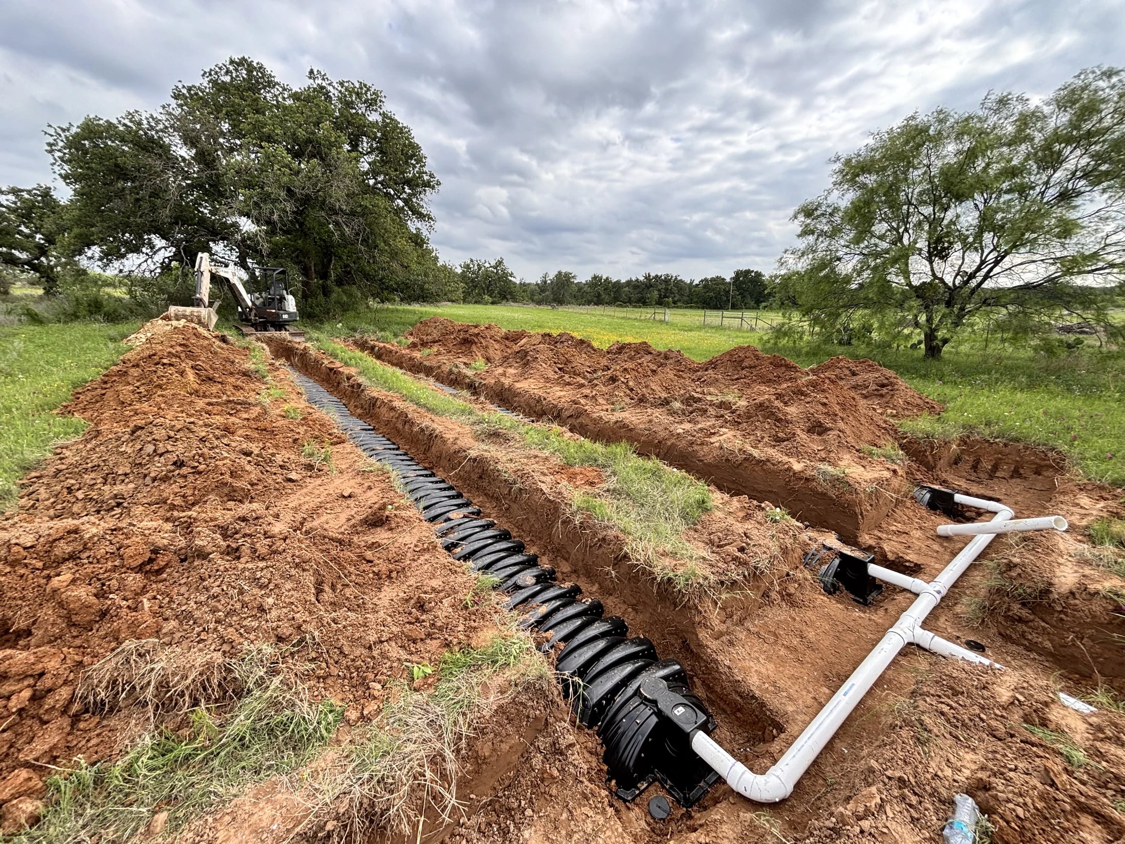 Excavated drainfield trenches with chamber rows and connecting piping