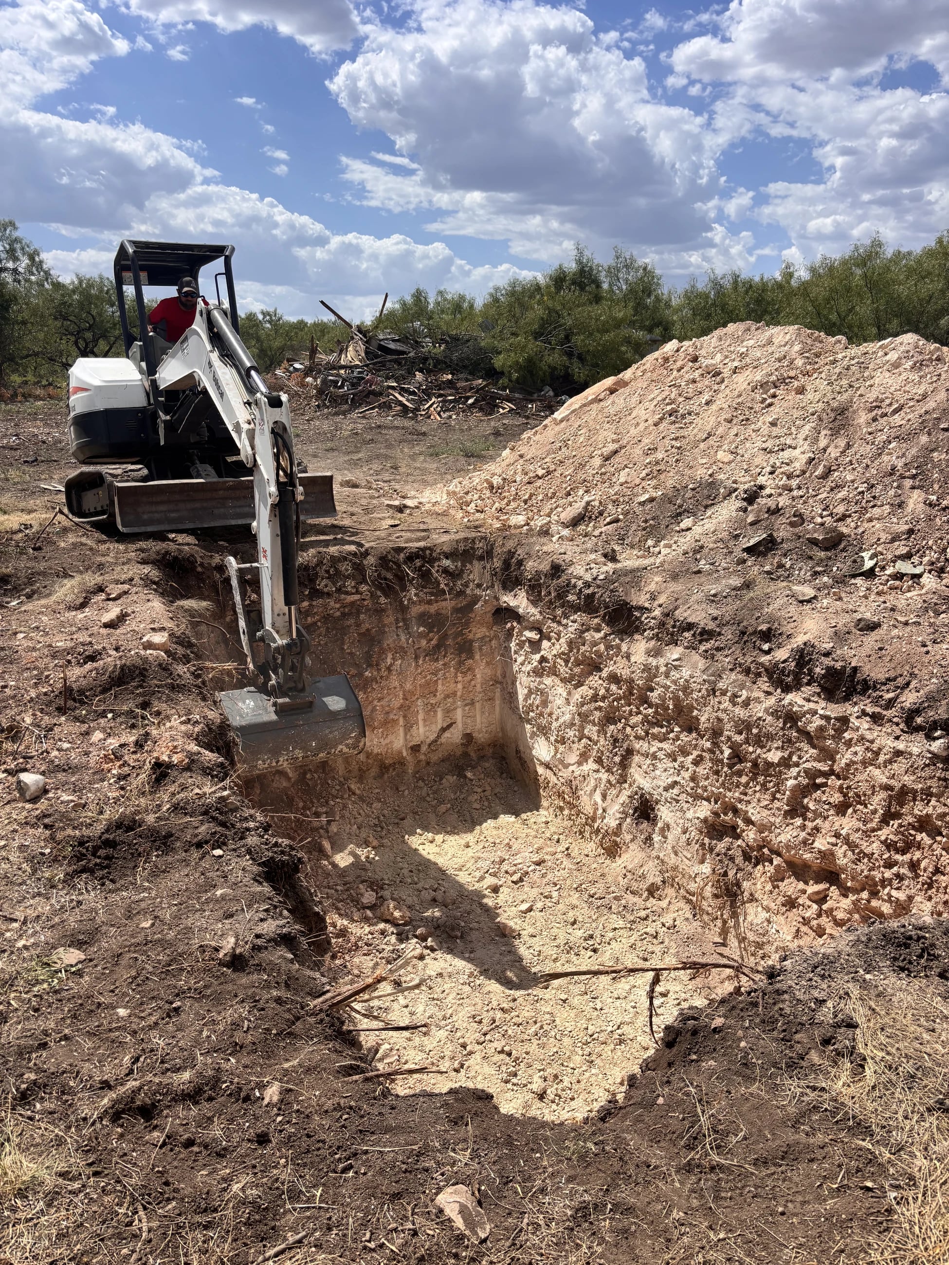 Excavator operator digging a tank hole at a Broyles Septic jobsite