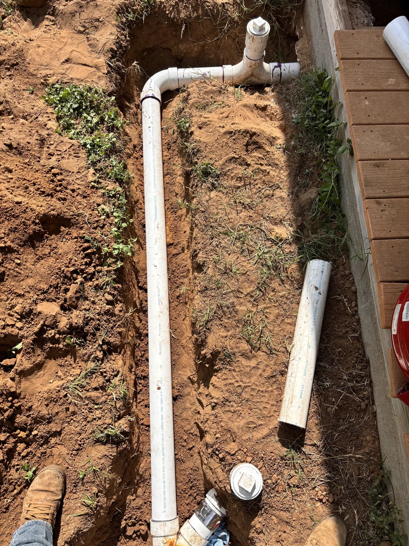 White septic piping laid in an open trench beside a building