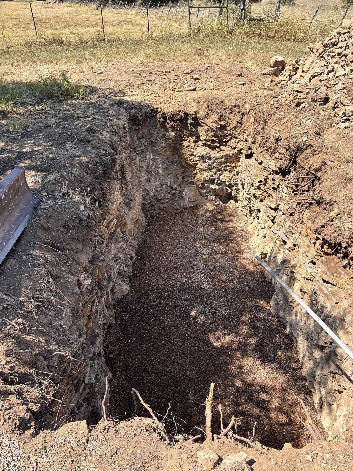 Excavated pit in rocky terrain before septic installation
